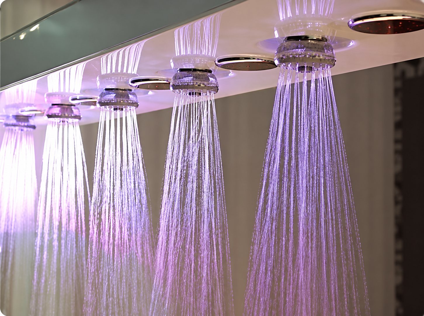 Rangée de pommeaux de douche à affusion sous un éclairage violet